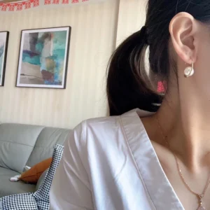 Alternative view of Stud earrings with oval gold structure with pearl in centre.