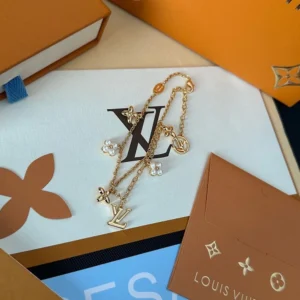 Linked chain bracelet with metallic charms and pearls.