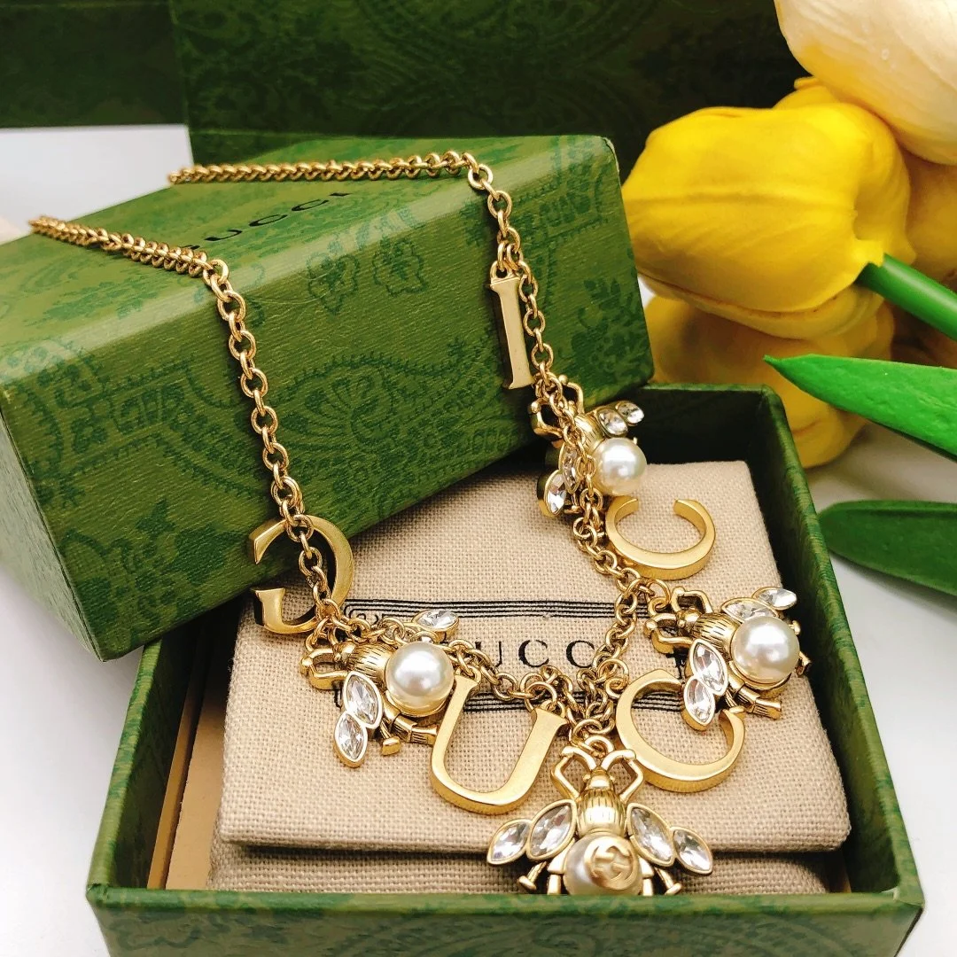 Golden linked chain necklace with metal cutout and bee charms made of pearls and diamonds. - Image 3