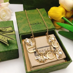 Golden linked chain necklace with metal cutout and bee charms made of pearls and diamonds.