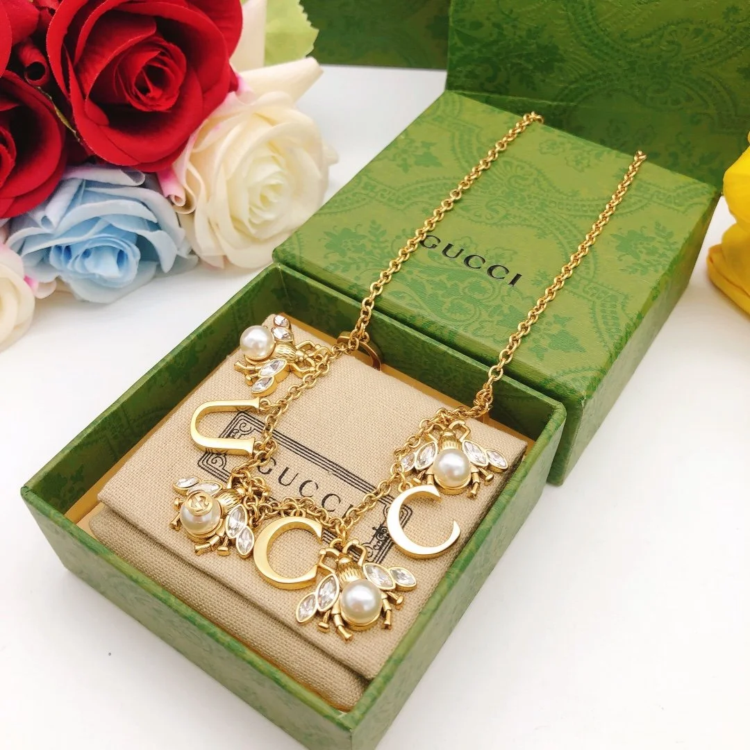 Golden linked chain necklace with metal cutout and bee charms made of pearls and diamonds. - Image 2
