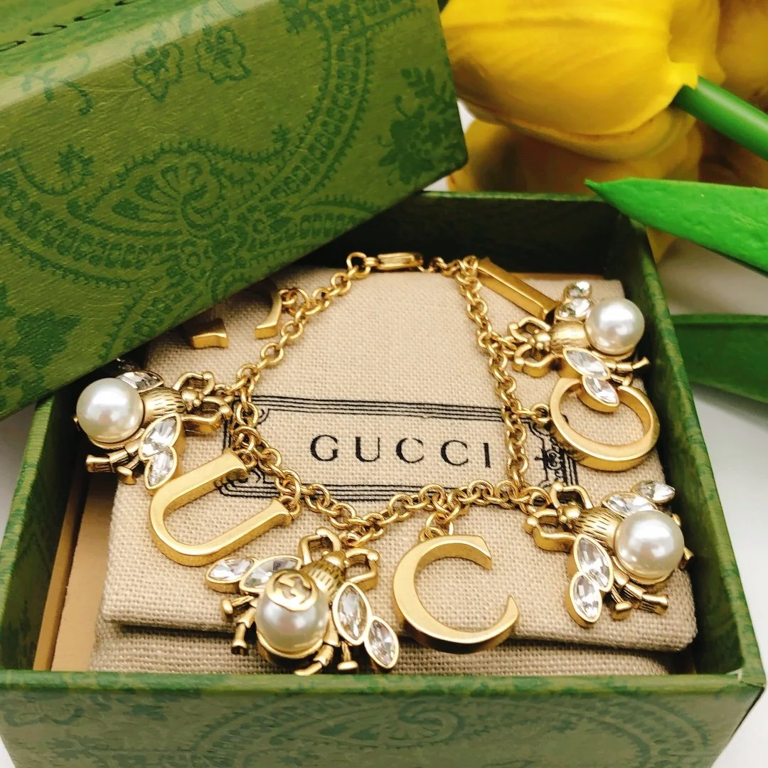 Golden linked chain bracelet with metal cutout and bee charms made of pearls and diamonds. - Image 3