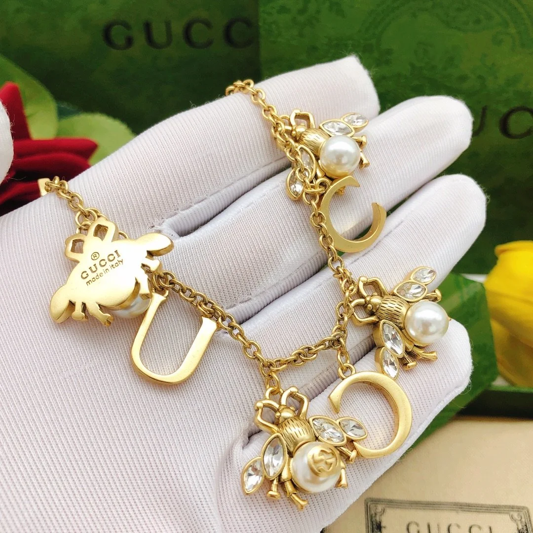 Golden linked chain necklace with metal cutout and bee charms made of pearls and diamonds. - Image 4