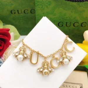 Golden linked chain bracelet with metal cutout and bee charms made of pearls and diamonds.
